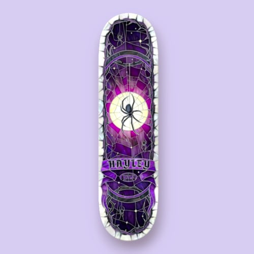 Skateboard deck med violet og sort farvetema, der viser et spindelvæv med en stor sort edderkop foran en gul cirkel, omgivet af mindre edderkopper og teksten "Hayley". (2)