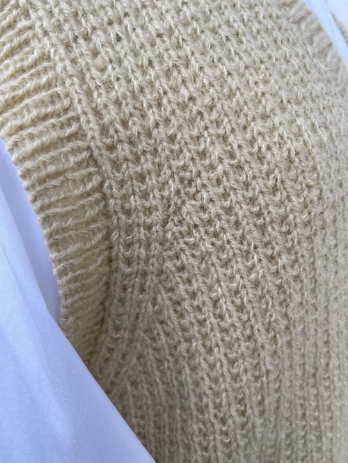 Nærbillede af beige strikket vest med ribkant over hvid skjorte. (6)