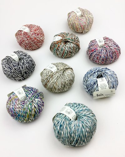 Ni farverige nøgler garn i forskellige flerfarvede kombinationer arrangeret på en hvid overflade.