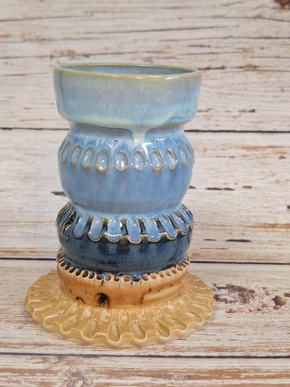 Keramisk vase med bølget ornamentik i blå og beige nuancer på træbord.