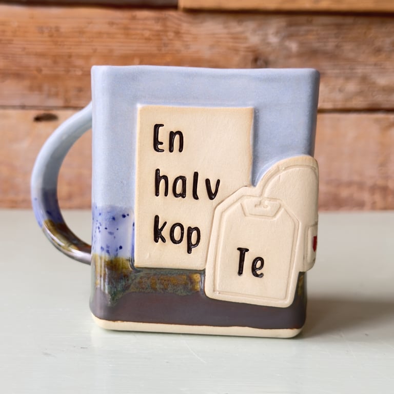 Krukke med motiv af tepose og tekst "En halv kop Te" på dansk.