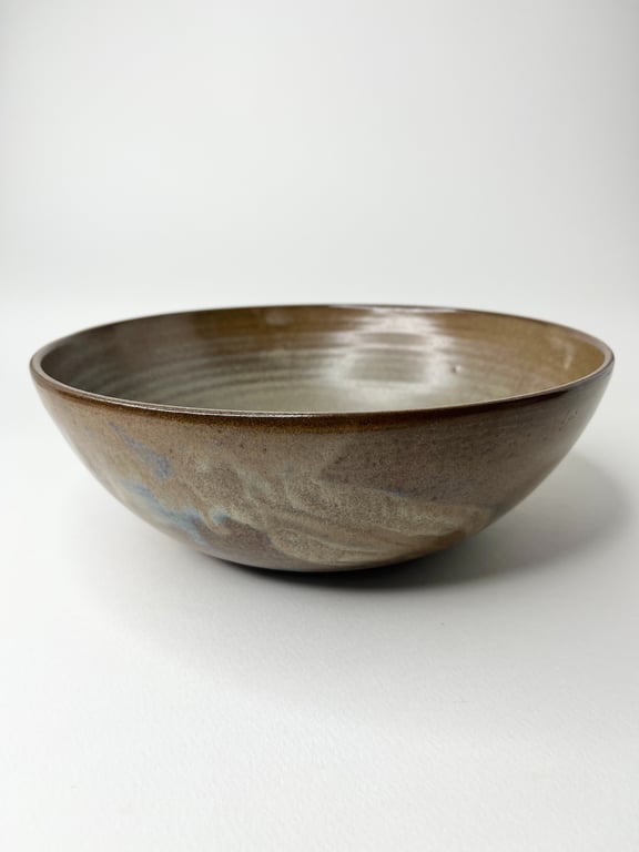 Brun keramisk skål med glaseret overflade og let mønster, placeret på hvid baggrund.