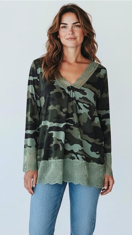 Kvinde iført camouflage-mønstret bluse med blondekant ved ærmer og hals, samt blå jeans, foran en lys baggrund.