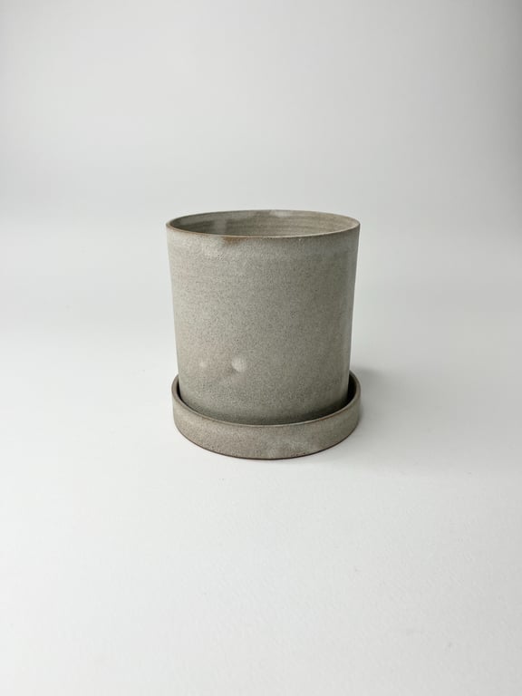 Grå keramisk urtepotte med underkop på hvid baggrund.