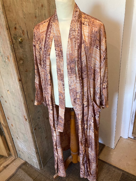 Lang kimono med brune og beige mønstre, vist på en hvid mannequin i et rustikt rum. (2)