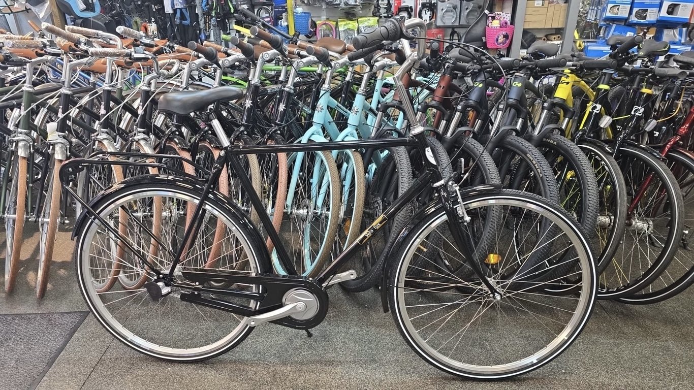 Billede af en sort klassisk bycykel, der står forrest i en række af forskellige cykler i en cykelbutik.