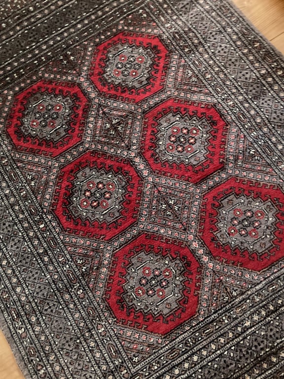 Mønstret tæppe med røde og grå ottekantede figurer og detaljerede geometriske mønstre. (2)