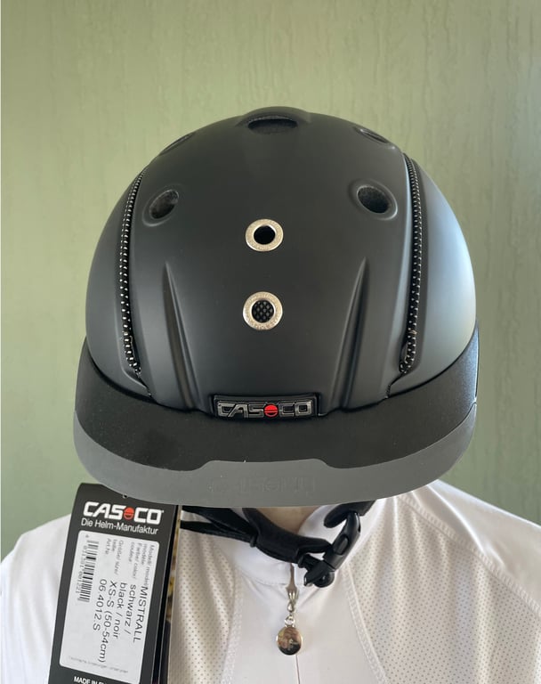 Person iført sort Casco cykelhjelm set forfra med prismærke hængende i siden.