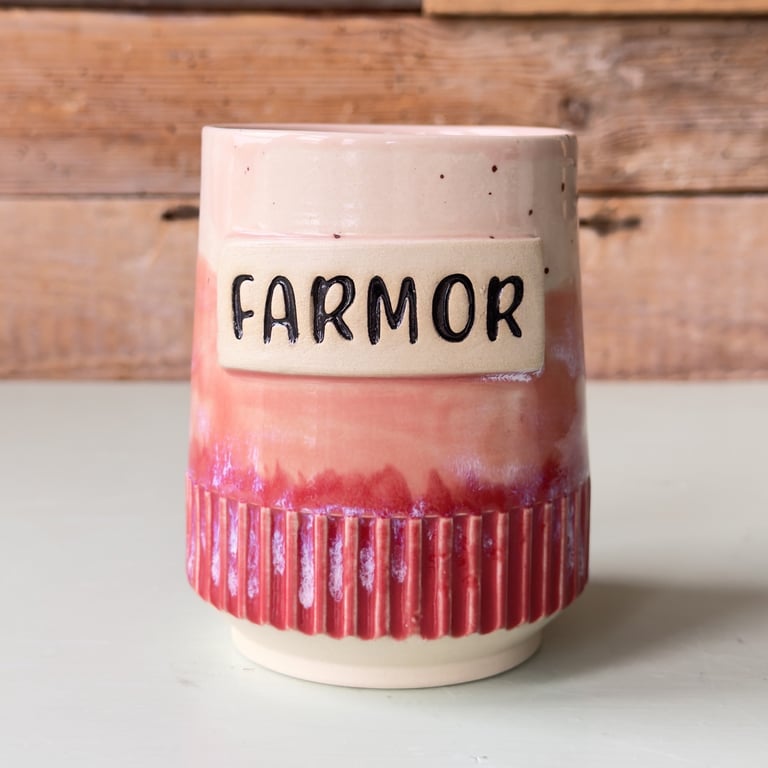 Keramikkrus med farvede nuancer i beige og rød med teksten "FARMOR" på fronten.