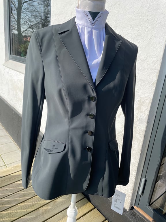 Grå ridejakke på mannequin med hvid ridetrøje under, fotograferet udendørs i solskin.