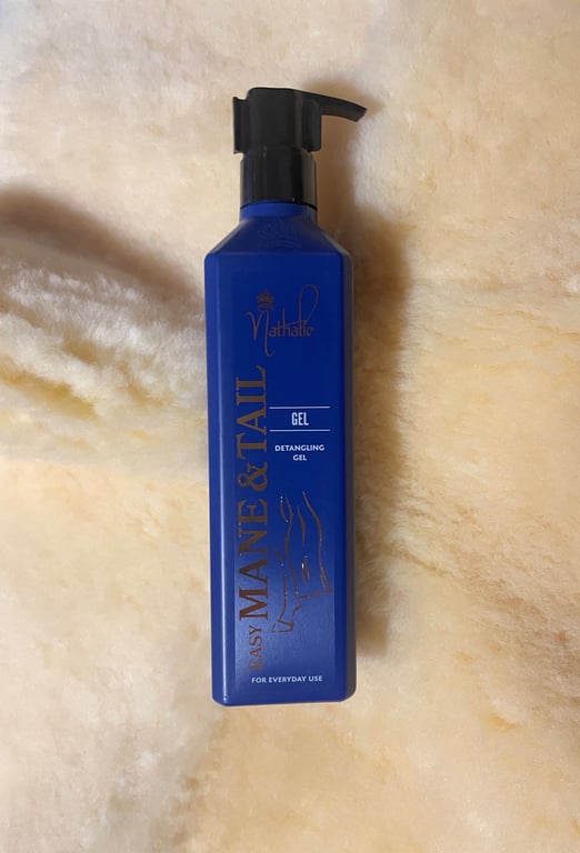 Blå pumpeflaske med Nathalie Easy Mane & Tail detangling gel til hverdagsbrug, placeret på en beige blød overflade.