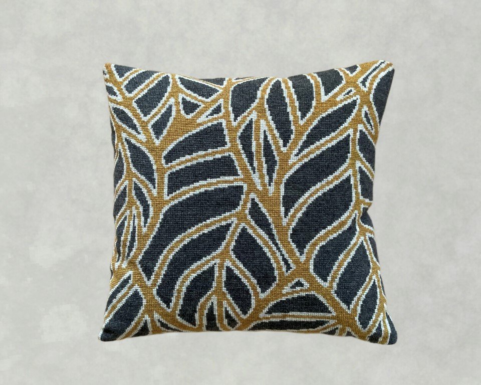 Pude med mønster af blade i sort, brun og hvid på grå baggrund.