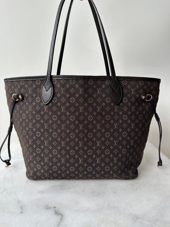 Brun Louis Vuitton taske med monogrammønster og to sorte skulderremme, stående på en marmorflade.