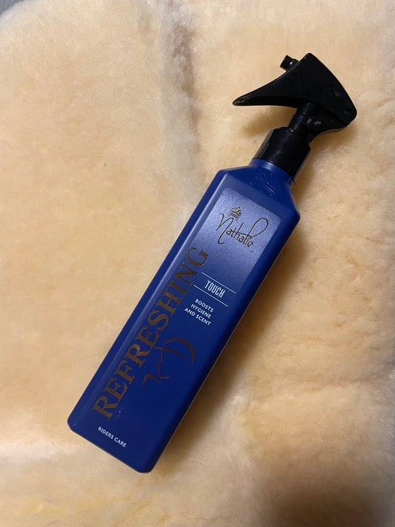 Blå sprayflaske med mærket "Refreshing Touch" fra Nathalie, placeret på en beige uldoverflade.