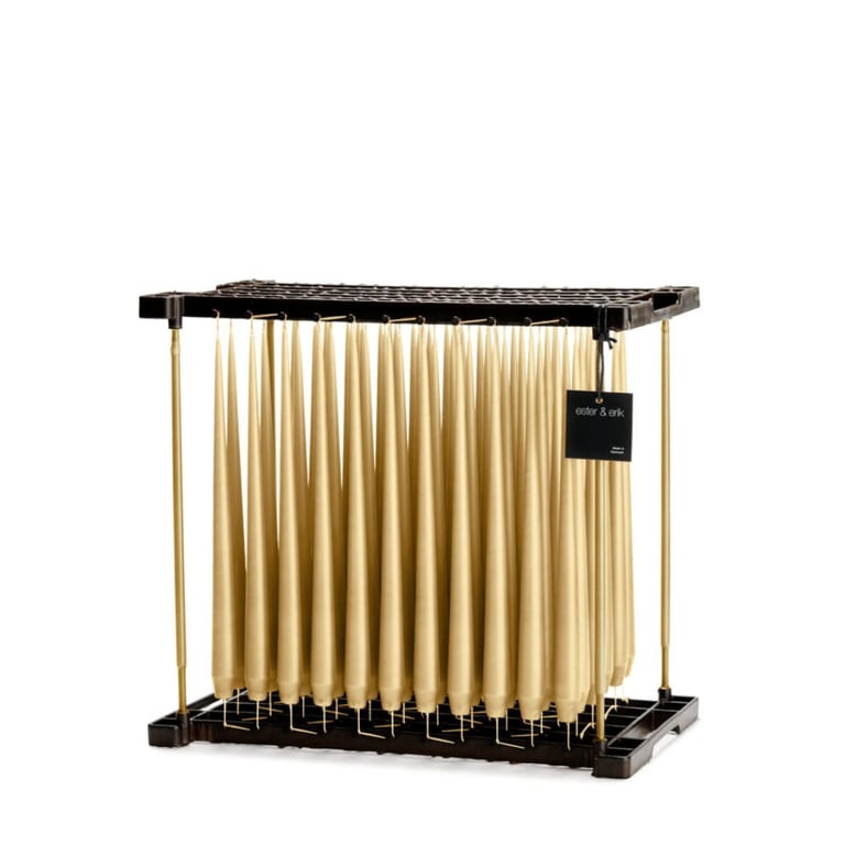 Billede af beige, spidse stearinlys hængende til tørring på en sort ramme med messingstænger, med et lille sort mærke der siger "æster & erik".