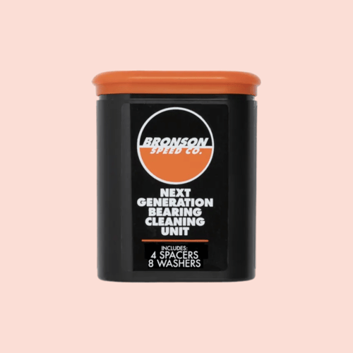 Sort og orange Bronson Speed Co. enhed til rengøring af kuglelejer med tekst på forsiden mod lyserød baggrund. (1)