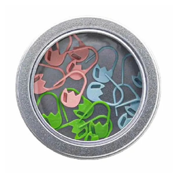 Rund metalæske med gennemsigtigt låg indeholdende farvede maskemarkører i lyserød, blå og grøn.