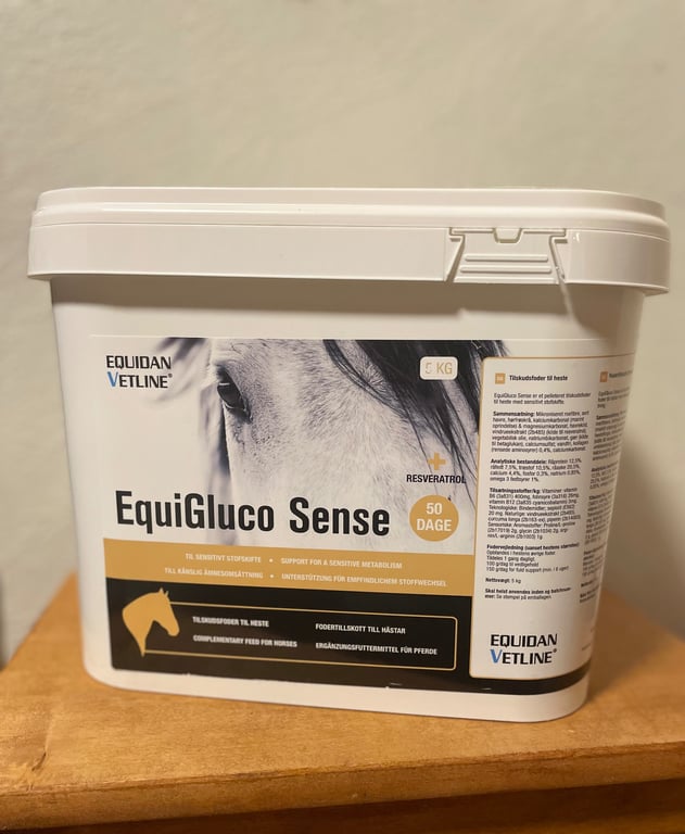 Plastbeholder med tilskudsfoder EquiGluco Sense fra Equidan Vetline, til heste, med billede af en hests øje på etiketten.