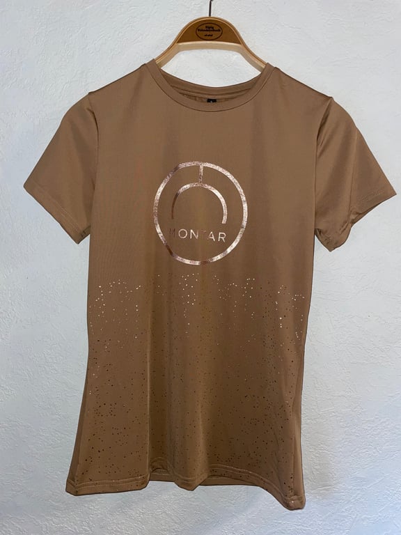 Brun t-shirt med kortærmer og logoet "MONTAR" i midten, hængende på en træbøjle mod en hvid væg.