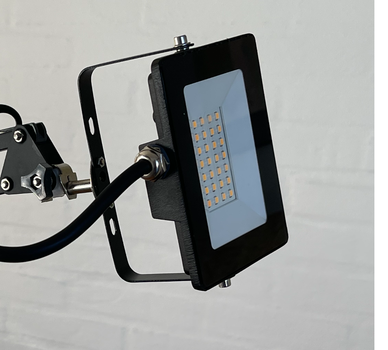 Sort LED-arbejdslampe monteret på en justerbar arm mod hvid væg.