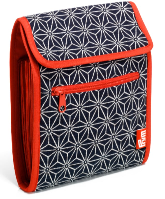 Sort og hvid mønstret stofpose med røde kanter, lynlås og foldet design.