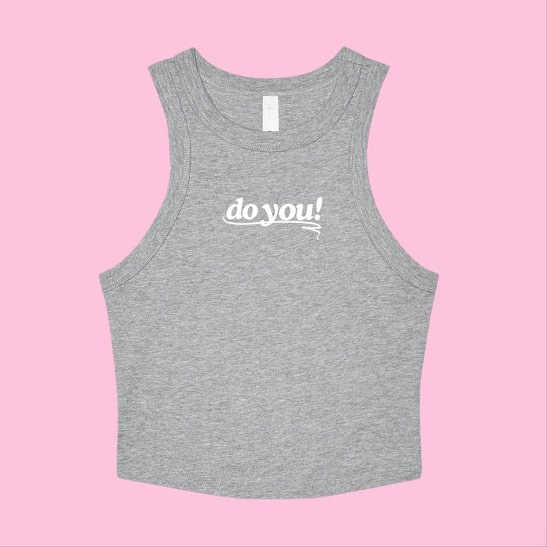 Grå ærmeløs crop top med teksten "do you!" i hvid på brystet, lagt fladt på lyserød baggrund.
