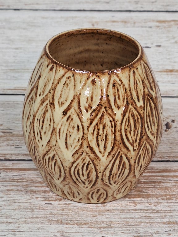 Keramisk vase med brunligt beige bladmønster på træbord.