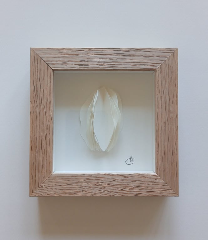 Billede af hvidt, 3D-kunstværk med bløde former i en lysebrun træramme mod en hvid baggrund.