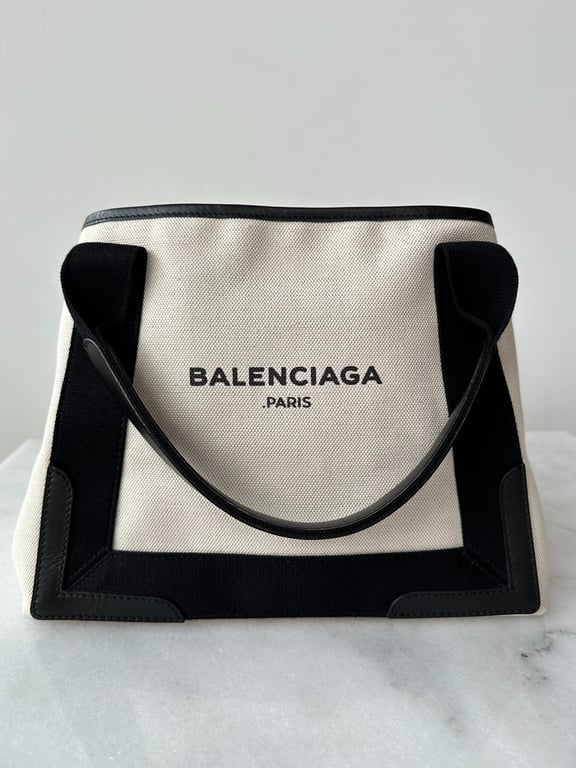 Beige og sort Balenciaga Paris taske i tekstil og læder, stående på en marmoroverflade.