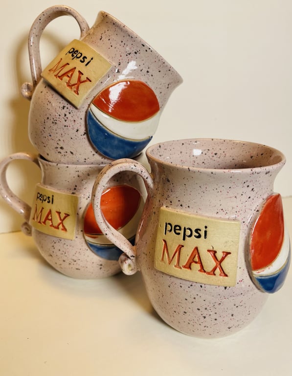 Tre keramikkrus med Pepsi Max-logo og farvet Pepsi-emblem på en lys overflade.