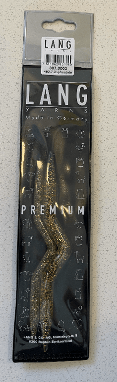 Sort og gennemsigtig emballage med et par gyldne, krøllede strikkepinde fra Lang Yarns, fremstillet i Tyskland, mærket "Premium".