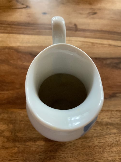 Hvid keramisk mælkekande med håndtag, set oppefra på et træbord. (5)