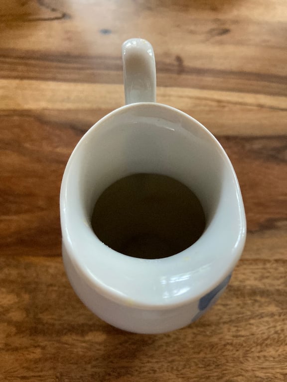 Hvid keramisk mælkekande med håndtag, set oppefra på et træbord. (5)