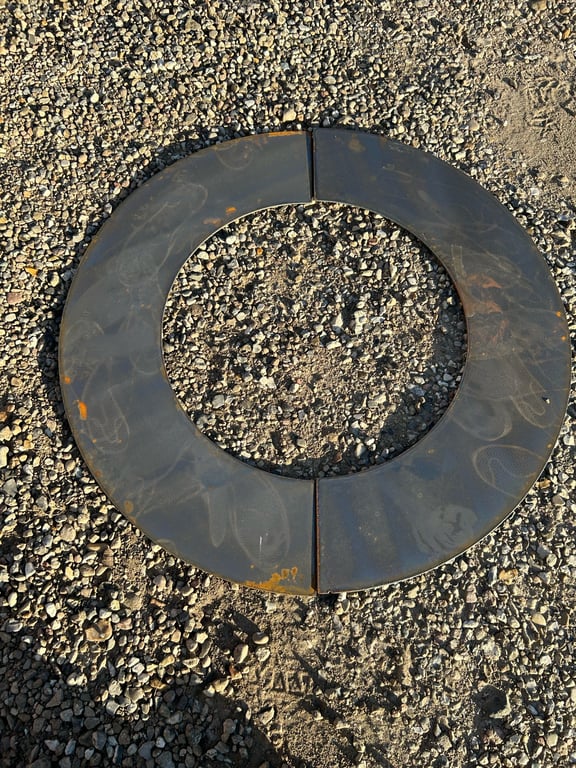 To metalplader formet som en cirkel ligger på grusbelagt jord.