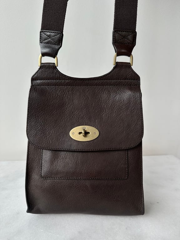Brun skuldertaske i læder med justerbar sort rem og guldfarvet drejelås.