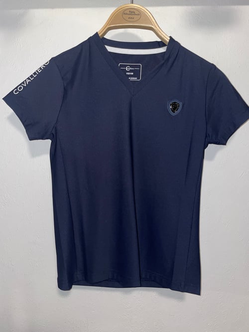 Marineblå t-shirt med V-hals, lille logo på venstre bryst og teksten "COVALLIERO" på højre ærme, hængende på en træbøjle. (1)