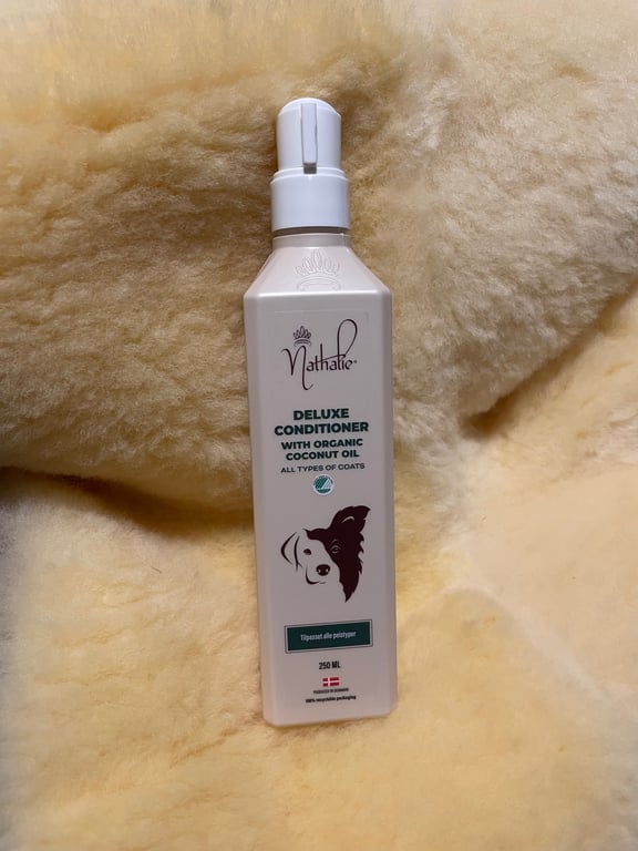 Flaske med Nathalie Deluxe Conditioner med økologisk kokosolie, designet til alle typer pels, placeret på en blød, lys baggrund.