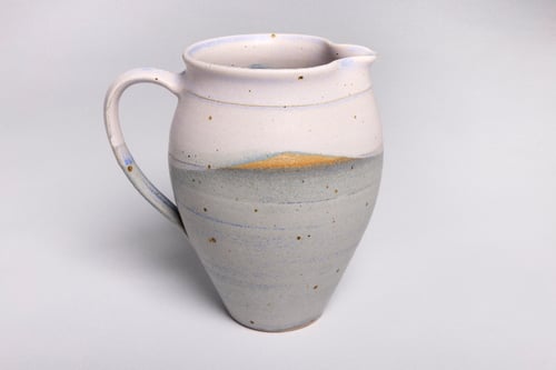 Keramisk kande med rund form, hvid og grå glasur med brune pletter og blå detaljer.