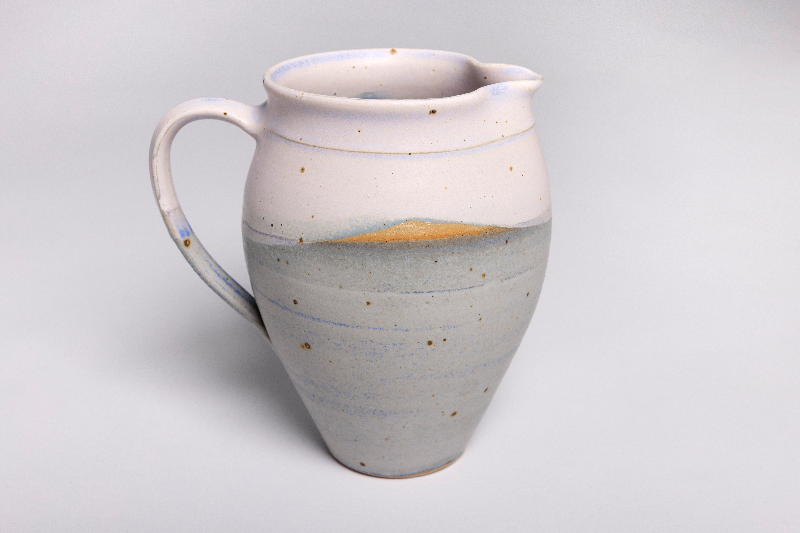 Keramisk kande med rund form, hvid og grå glasur med brune pletter og blå detaljer.
