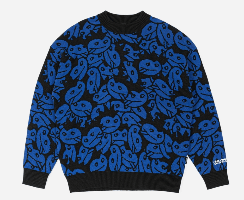 Blå og sort trøje med mønster af grove, tegneserieagtige ansigter.