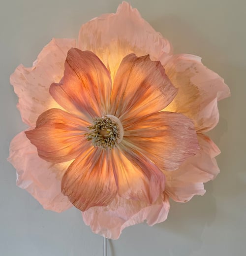 Stor dekorativ lampe formet som en lysende orange og lyserød blomst monteret på en væg. (1)