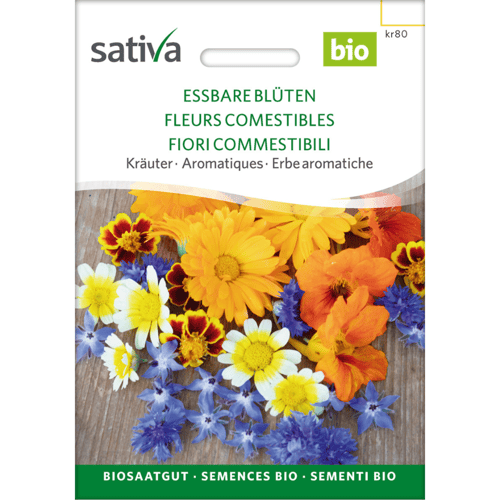 Billedet viser en pakke med økologiske spiselige blomsterfrø fra mærket Sativa med blomster i forskellige farver som gul, orange, blå og hvid. Tekst på pakken er på flere sprog, herunder dansk, tysk, fransk og italiensk. (1)