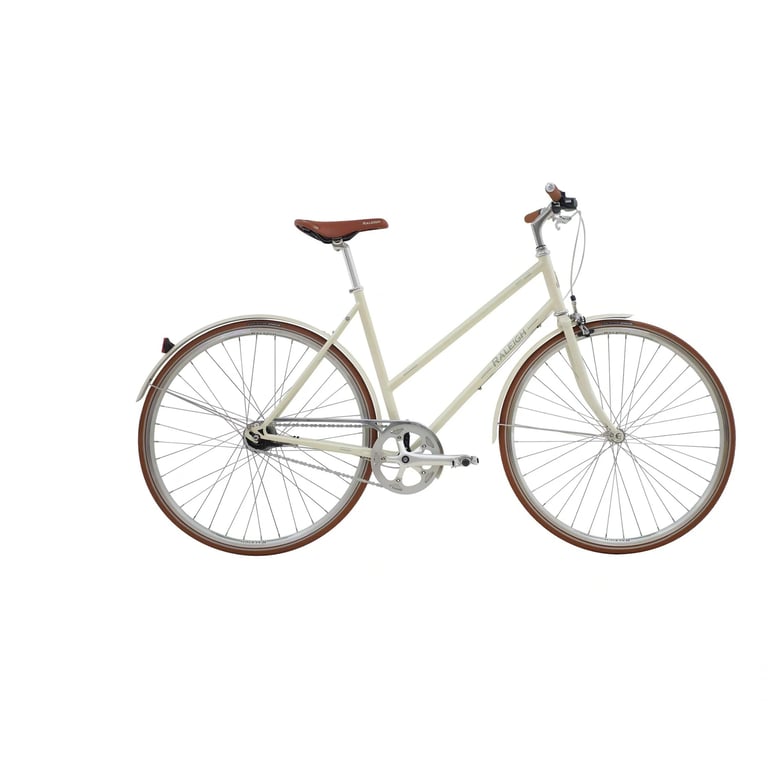 Billede af en beige vintage damecykel med brunt sæde og håndtag, læderindfattede dæk og sølvfarvet stel mod hvid baggrund.