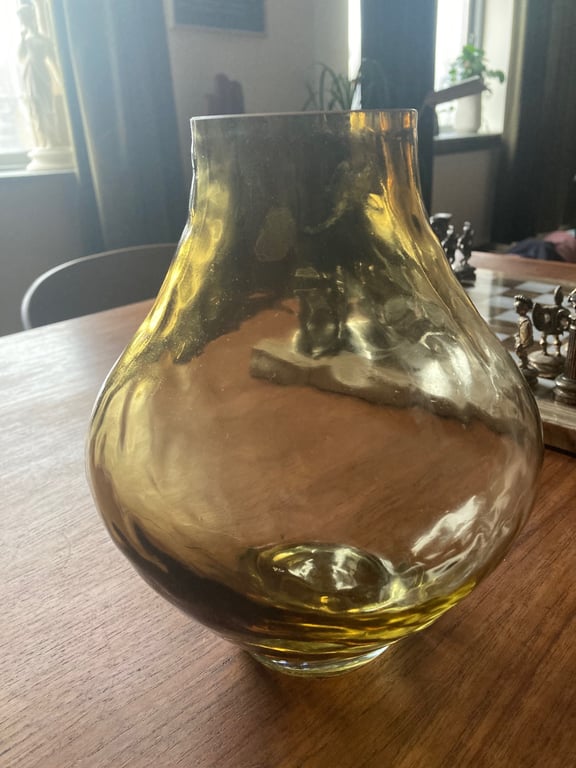 Gennemsigtig gul glasvase på et træbord med et skakspil i baggrunden. (2)