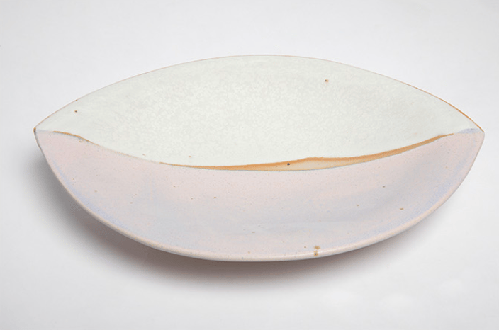 En hvid, oval skål med en sprækker langs kanten, der er lavet af keramik.