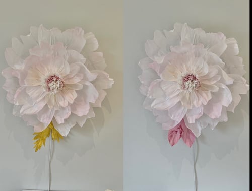 To store kunstige blomster i lyse pastelfarver, den ene med gule blade, den anden med lyserøde, begge monteret på væg med ledninger. (1)