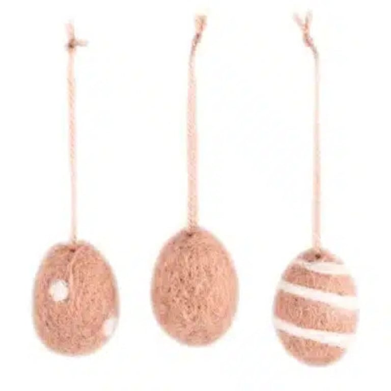 Tre påskeæg lavet af flettet naturmateriale, hængende i snore mod en hvid baggrund.