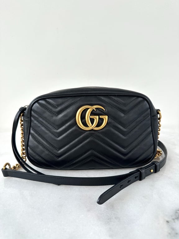 Sort Gucci skuldertaske i quiltet læder med guld farvet dobbelt G-logo og justerbar rem med guldkæde.