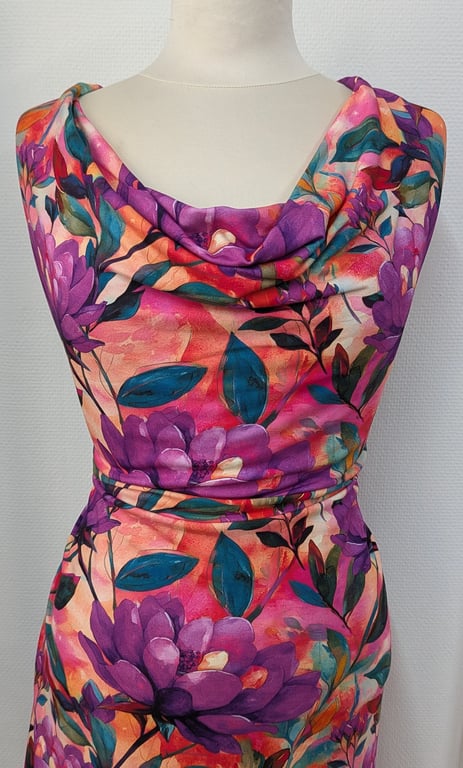 Farverig blomsterkjole med draperet hals på hvid mannequin mod hvid væg.