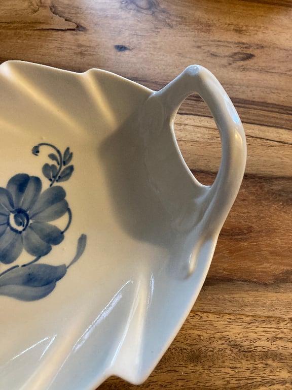 Hvidt keramisk fad med blå blomsterdekoration og hank, placeret på træbord. (4)